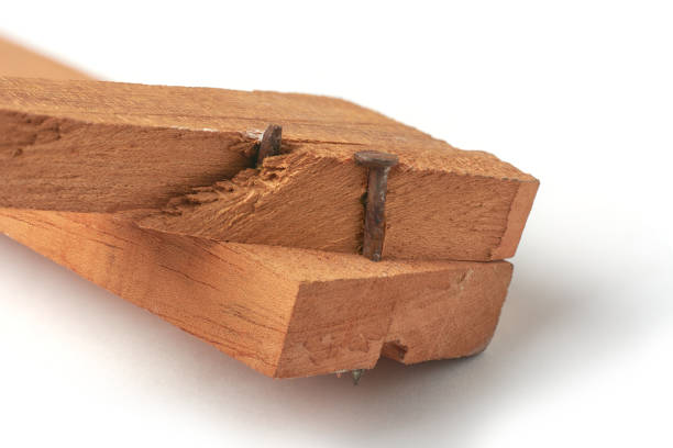 two wood pieces joined with large rusty nails driven through and protruding from bottom piece, wood is broken and splintered near one nail, unprofessional and careless woodworking method