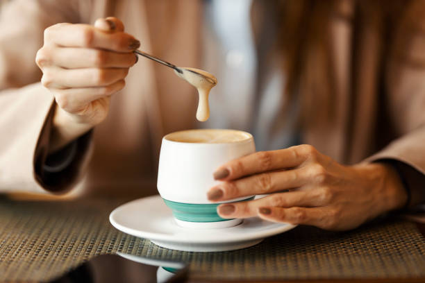 istock Close up of hands stirring coffee with tea spoon in cafe. 2196364490