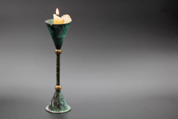 Stock photo showing elevated view of lit diya (oil lamp), with flickering flame in the dark, part of Diwali festival of lights celebration.