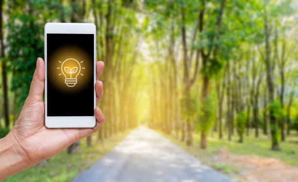 Green energy logo on smartphone over blurred green forest background, environment background idea
