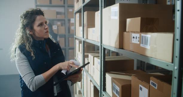 istock Female Warehouse Associate Scans Cardboard Box, Checks Inventory on Tablet Computer 2196367210