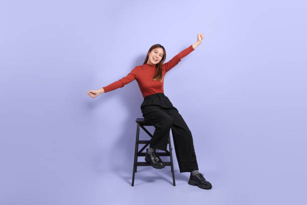 The young Southeast Asian woman in casual clothes, standing against a purple background.