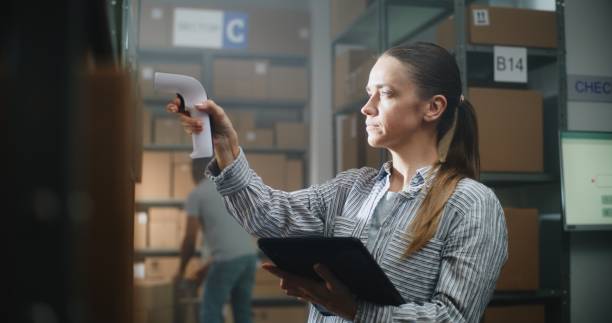 istock Female Warehouse Associate Scans Cardboard Boxes, Checks Delivery Information on Tablet Computer 2196372387
