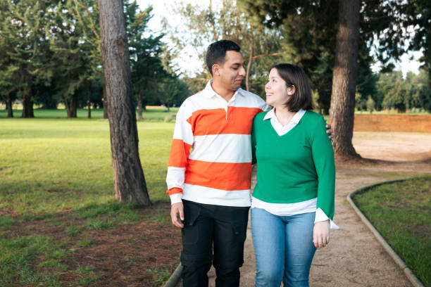 Loving young Latino couple walking together in a lush green park, sharing a moment of togetherness and connection