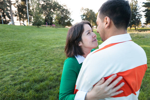 A tender Latino couple lock gazes as they embrace lovingly amidst the greenery of a peaceful park setting