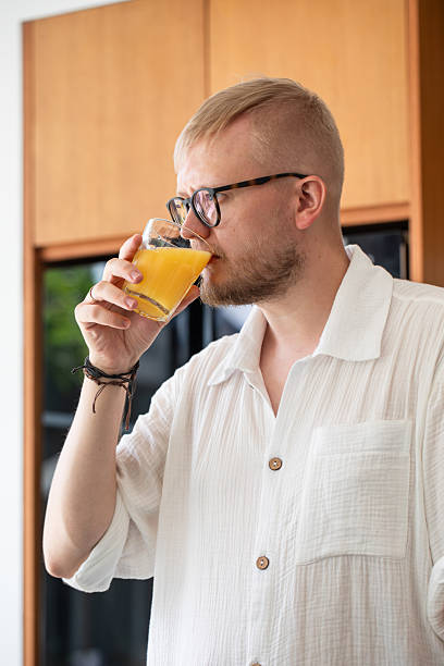 istock man against the background of a modern kitchen drinking orange juice, soft drink 2196376026
