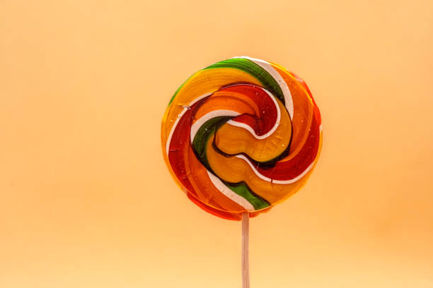 istock Brightly colored swirl lollipop against a yellow background. 2196377482