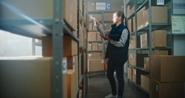 istock Female Sorting Center Employee Scans Parcels, Takes Package for Delivery to Client 2196379619