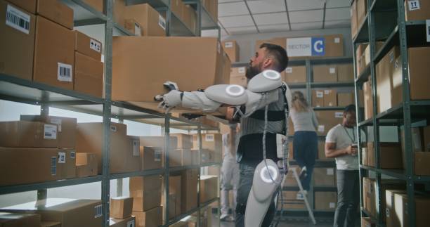 istock High-Tech Warehouse: Worker in Full Body Robotic Exoskeleton Puts Cardboard Box on Shelf 2196380626