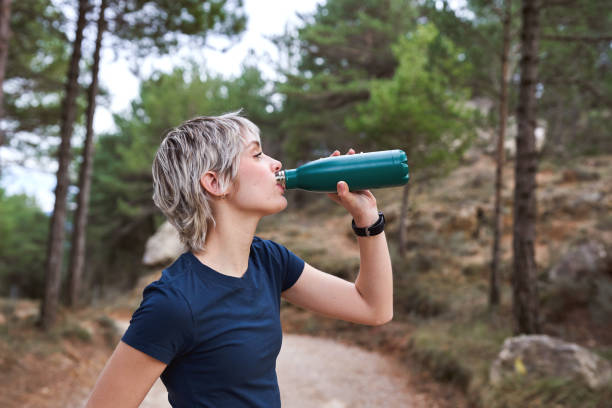 istock Young woman drinking water from a bottle while hiking in a forest. 2196382534