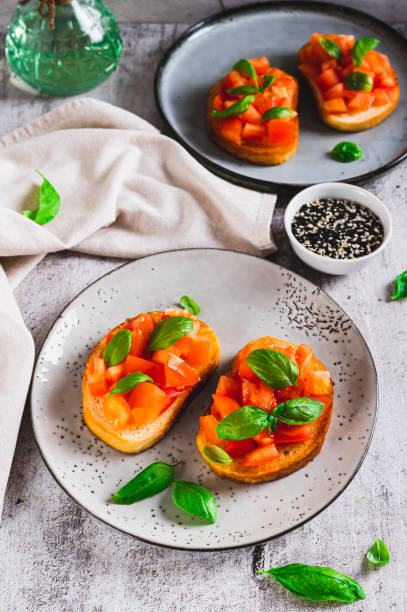 istock Italian sandwiches with tomatoes, basil and garlic on a plate on a table vertical view 2196383521