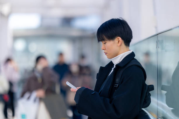 Young freelance worker using smart phone on pedestrian walkway in city