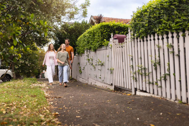 istock Smiling Family Walking Alongside a Path Near a White Picket Fence 2196383951