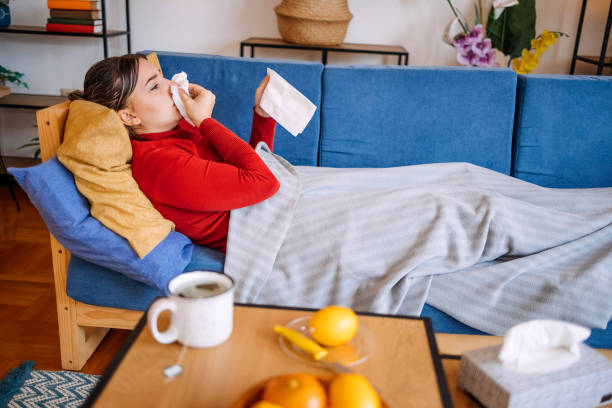 istock Young female adult lying on sofa bed at home feeling sick and using tissue 2196384087