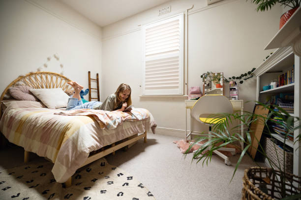 istock Cozy Bedroom with Young Girl Relaxing on Bed Using Her Smartphone 2196388570