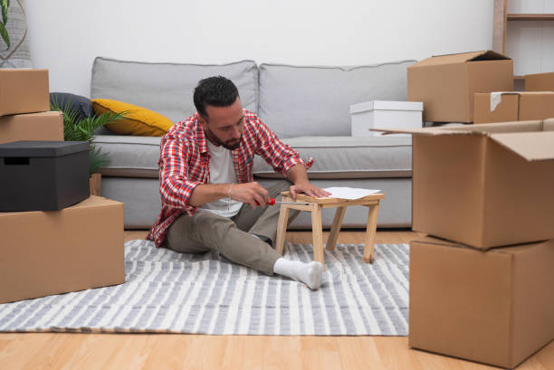 istock young man assembles DIY shelf moving carton boxes, resourcefulness in his new home after relocating 2196389098