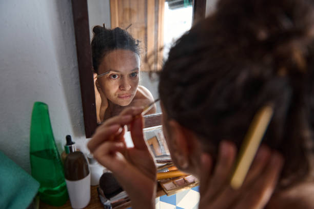 istock Woman carefully tweezing eyebrows while looking at a mirror in the bathroom 2196389267