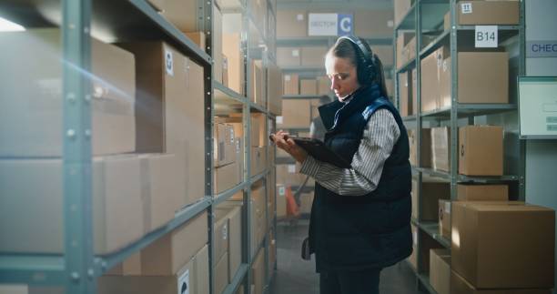istock Female Inventory Manager Wearing Headset Scans Parcels in Warehouse Facility 2196391679