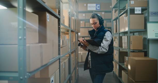 istock Female Inventory Manager Wearing Headset Scans Parcels in Warehouse Facility 2196392040