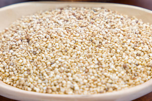 Close up of quinoa seeds in wooden bowl on wooden table.