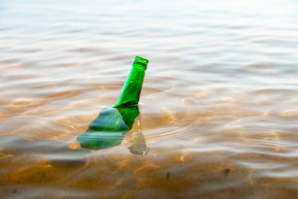 istock Green glass bottle floating in a river, bottleneck seen over water surface. 2196395819