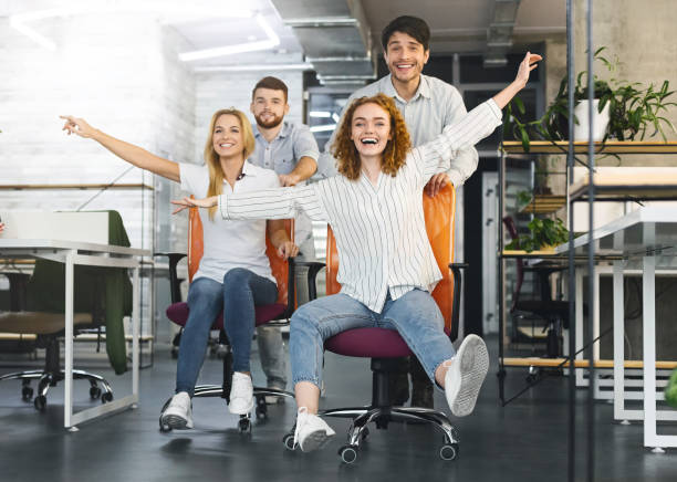 istock Happy colleagues having fun at workplace, making office chair race 2196397314