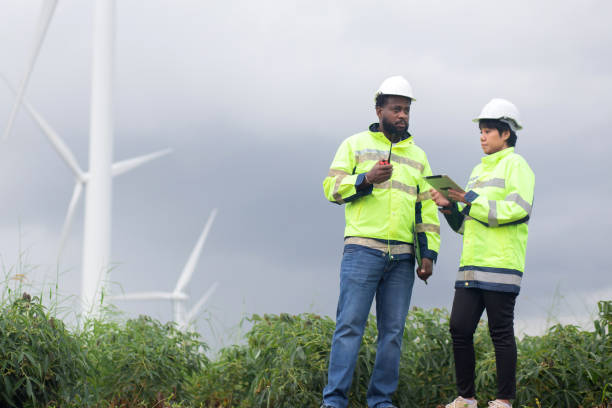 istock Two engineer check and examining wind turbines in wind farm, renewable energy and teamwork in a sustainable environment, inspection power electric with document and tablet, industry and eco. 2196398786