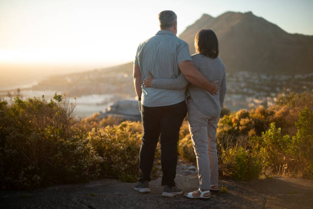 istock Couple, mountain and back with hug, sunrise and memory with care, connection and support in summer. Mature people, outdoor and love with embrace on hill with partner, nature and bonding on vacation 2196399633
