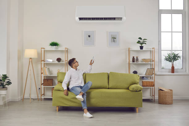 istock Man switching air conditioning modes sets comfortable temperature while enjoying fresh air at home. 2196404795