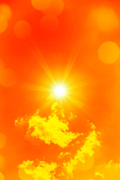 Bright sun with beautiful beams and bokeh lights in the sky with some clouds. Toned in red color, space for copy.