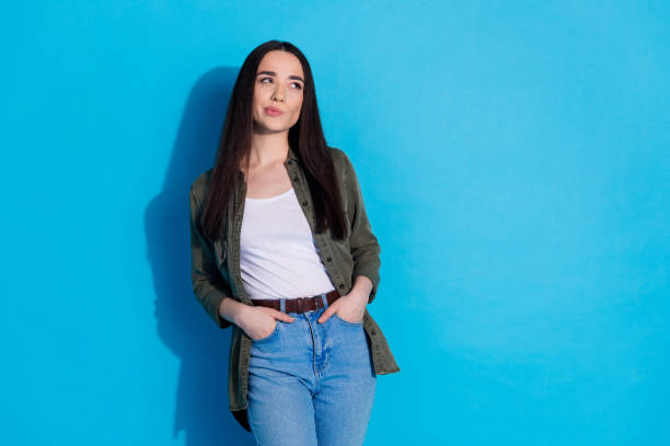 istock Young woman standing against blue background in casual outfit with thoughtful expression 2196405529