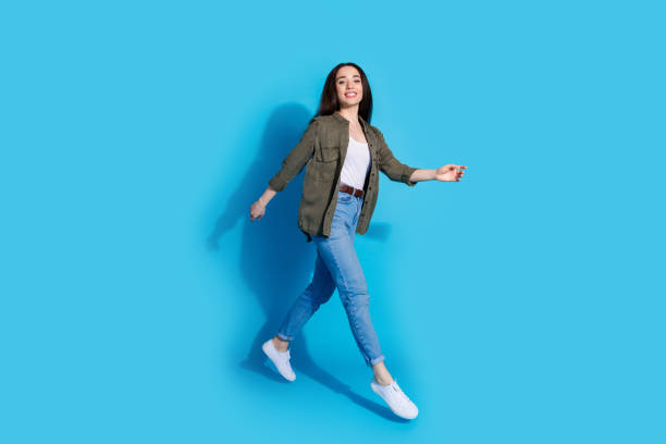 istock Confident young woman walking with a smile on a bright blue background 2196405989