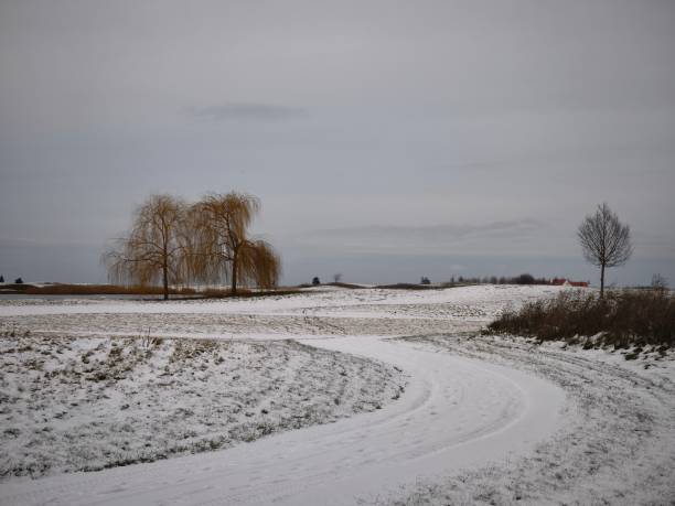 istock Winding snow covered path traversing barren winter landscape, leafless trees framing distant home against overcast prague skyline Golf Vinor 2196408463