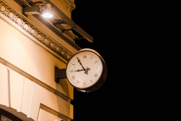 a street clock on the wall of a building covered in snow showing five minutes to nine
