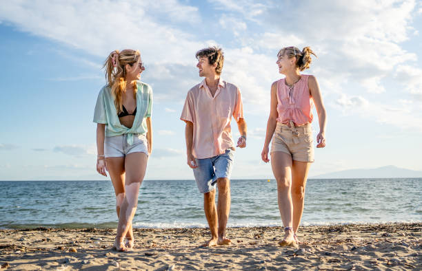 istock Young friends walking on the beach 2196416561