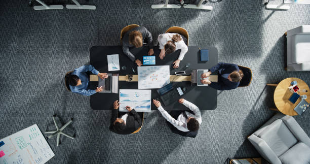 istock Top Down View: Diverse Professionals Working on Business Statistics Reports and Digital Plans in an Office. Discussion and Data Analysis on Laptops and Charts. Teamwork, Innovation Concept 2196417559