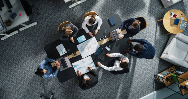istock Diverse Professionals Working on Business Statistics Reports and Digital Plans in an Office. Top Down View of Discussion and Data Analysis on Laptops and Charts. Teamwork and Innovation Concept 2196417605