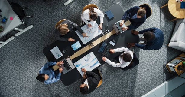 istock Diverse Professionals Working on Business Statistics Reports and Marketing Plans in an Office. Top Down View of Discussion and Financial Data Analysis on Laptops and Charts. Teamwork and Innovation 2196417663