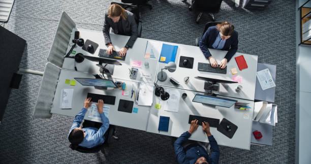 istock Top Down View of Multiethnic Team in a Corporate Office, Working on Desktop Computers and With Financial Documents. Colleagues Working Creating Reports, Developing Business Strategies for Hedge Fund 2196418167