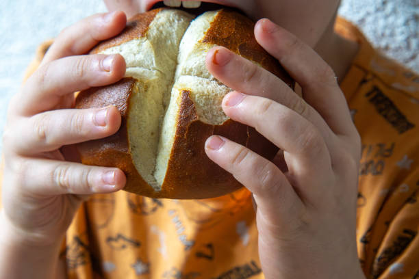 istock a child holding a dry kaiser roll in his hands. little boy while biting a dry roll. a small child's meal. 2196418189
