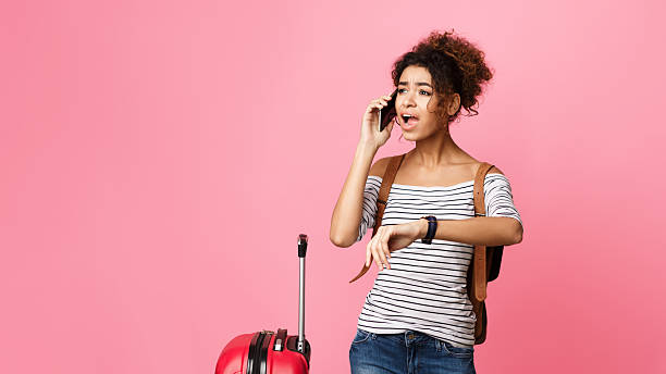 istock Young Traveler Checking Time While Talking on the Phone Against a Pink Backdrop 2196419652