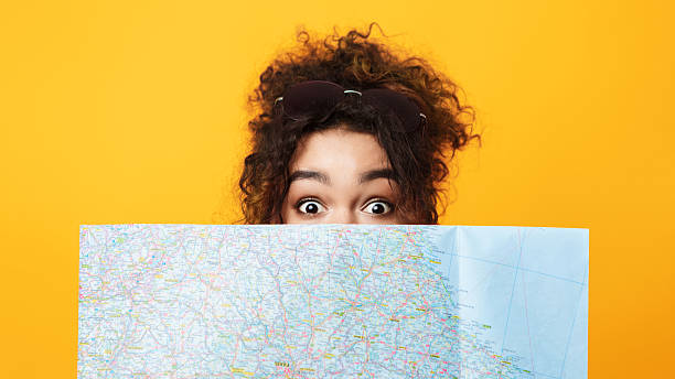 istock Person Exploring a Map With Excitement Against a Bright Yellow Background 2196419656