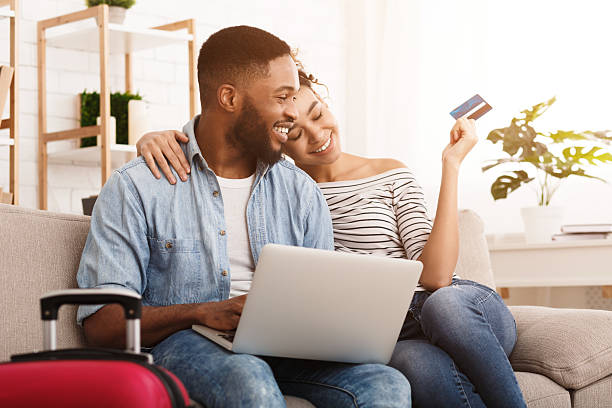 istock Young Couple Planning a Vacation While Sitting on a Couch With Luggage Beside Them 2196419685
