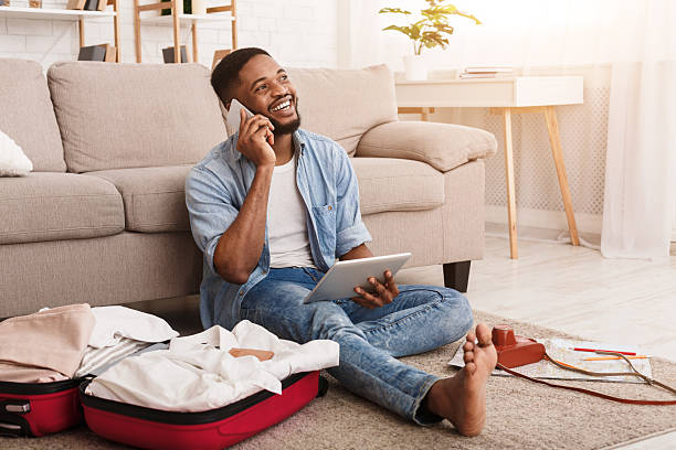 istock Happy Man Enjoying a Conversation While Preparing for a Trip in a Cozy Living Room 2196419702