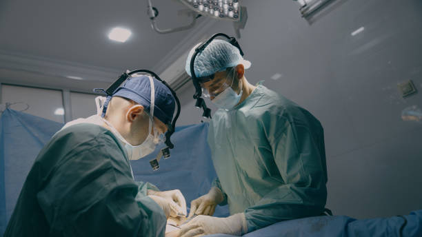 surgeon doctor with intern practitioner perform surgical operation men cut out appendicitis cancer tumor operate heart lungs stomach incision sew up wound surgery process in clinic hospital healthcare - blindtarmsinflammation bildbanksfoton och bilder