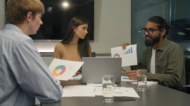 istock Team leader businessman coach showing corporate charts graphs on paper discuss analyze diagram graphic talk with colleagues diverse clients man woman listen business presentation at office conference 2196420689