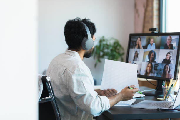 istock Man in Headphones on Video Conference Call, Reviewing Documents 2196422494