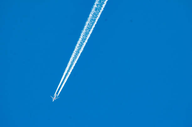 Jet plane leaves fuel trail in blue sky
