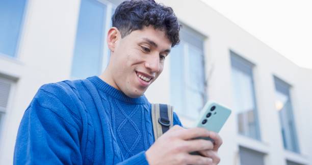 istock Smiling young man using smartphone outdoors near modern building 2196423808