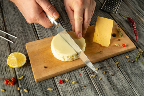 istock Hands of a chef with a knife cut cheese on a cutting board before preparing pizza. Gray space for recipe or menu 2196423879